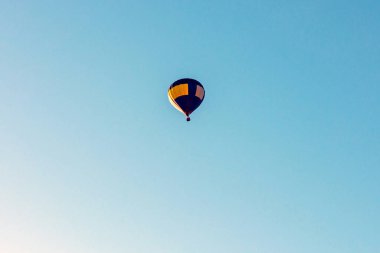 Sıcak hava balonu mavi bir gökyüzünde uçar. Mavi, sarı, sıcak hava balonu açık bir gökyüzünde. Anlaşıldı..