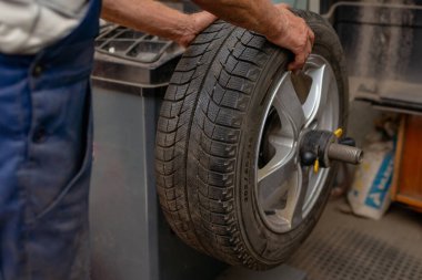 Araba tamircisi araba tekerleğini dengeliyor, otomobil tamir servisinde bilgisayar dengeleyicisinde lastik var. Özel bir ekipmanda tekerlek dengesi..