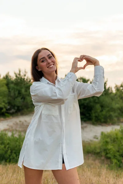 Νεαρή Γυναίκα Κάνει Χέρι Σχήμα Καρδιάς Έναν Κήπο Στο Ηλιοβασίλεμα — Φωτογραφία Αρχείου