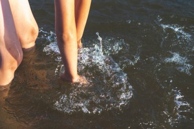 Küçük çocuk suda oynuyor ve gölde ya da nehirde hazırlanması ve damlalarla eğlenmesi için sükse yaptırıyor..