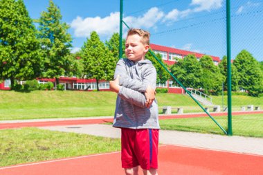 Basketbolcu çocuk sahada esneme hareketleri yapıyor. Çocuk ısınıyor. Güneşli bir günde Red Court Sokağı 'nda..