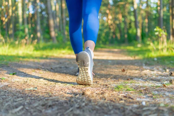 Athletic pair of legs running or jogging on a path during sunrise or sunset.Fitness Girl running at sunset in forest.Closeup.Copy space.