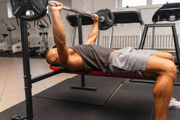 Bench Press Exercise.athletic man pumping up muscles on bench press at the gym.breast muscles pumping,workout.