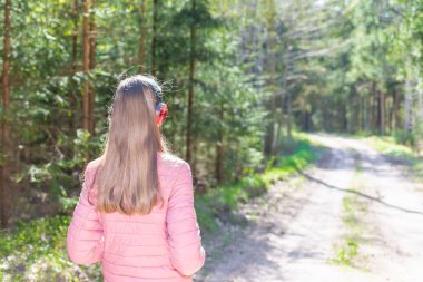 Sevimli, neşeli, sıska bir genç kız. Keyfini çıkarıyor, ormanda müzik dinliyor. Yaz, bahar günü ormanı ya da park alanında yürürken..