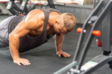 Şınav çeken genç sporcu. Spor salonunda egzersiz yapan kaslı ve güçlü bir adam. Spor kıyafetli genç yakışıklı bir adamın spor salonunda şınav çekmesi..