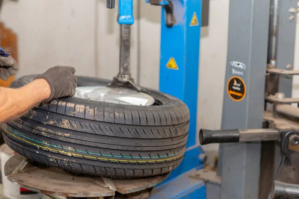 Mechanic changing tire in car service. Tire rotation machine.Car mechanic mounts tire on wheel in a workshop. tire installation in the workshop,closeup.