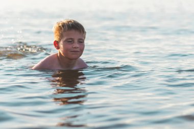 Mutlu kapalı göz çocuk suda yüzerken eğleniyor. Tatlı çocuk suda yüzerken rahatlıyor. Çocuk sahilde eğleniyor. Yaz tatili. Aktif yaşam tarzı konsepti. Yaz tatilindeki mutlu çocuk..