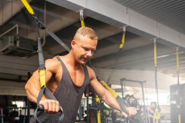 Spor salonunda egzersiz yapan kaslı bir adam, spor salonunda triseps egzersizi yapan. Güçlü çıplak erkek karın kası. Yakışıklı vücut geliştirici. Spor salonunda kapalı alanda çalışıyor..