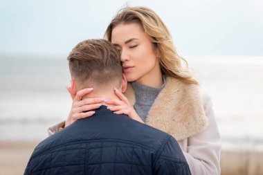 Baharda plajda genç ve şık bir çift. Birbirinize sarılın ve sıcak bir bahar akşamının tadını çıkarın..