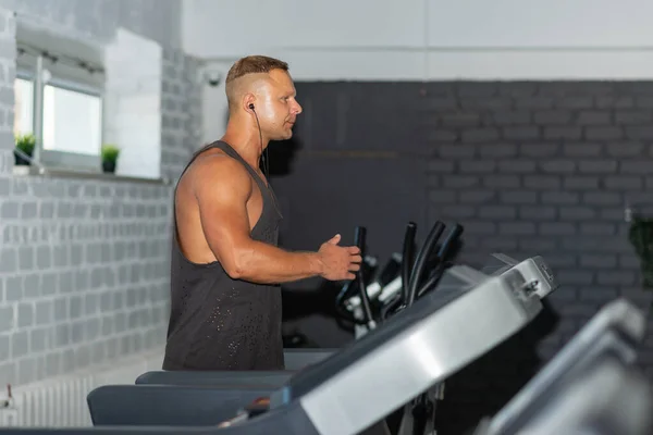 Young man in sportswear running on treadmill at gym.Handsome sport gym man running on the treadmill.Indoors shot.Man running in a gym on a treadmill.Exercising fitness.Healthy lifestyle concept.