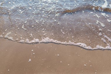 Kumlu akşam kumsalında denizin yumuşak dalgası. Odaklanma, bulanık görüntü. Boşluğu kopyala.