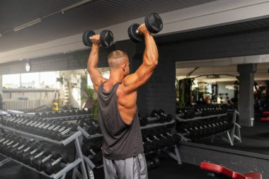 Spor salonunda aptal gibi egzersiz yapan genç ve formda bir adam. Sağlıklı bir adam aptallarla çalışıyor. Kapalı alanda çekim yapıyor..