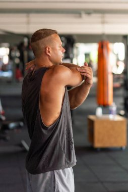 Spor salonunda spor salonu ısınıyor. Erkek spor salonunda ısınma egzersizi yapıyor. Spor salonunda esneme egzersizleri yapan bir fitness oyuncusunun portresi..