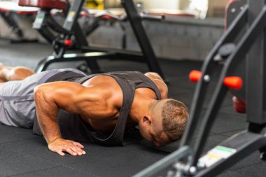 Şınav çeken genç sporcu. Spor salonunda egzersiz yapan kaslı ve güçlü bir adam. Spor kıyafetli genç yakışıklı bir adamın spor salonunda şınav çekmesi..