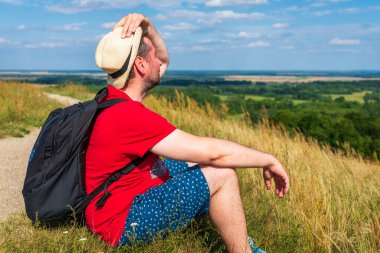 Gezgin erkek, sakin manzaralı meditasyon yapıyor. Orman manzarası yaz günü. Dağın tepesinden manzaranın tadını çıkaran bir adam. Rahat orta yaşlı bir adam doğası gereği yalnız. Yakın plan, yan görüş..