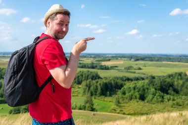 Yürüyüşçü yaz dağında bir ürün sunmak için yan tarafı işaret ediyor. Alan görüntüsü kopyala.