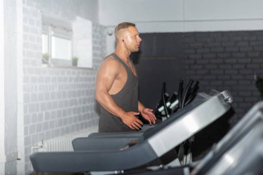 Spor giyimli genç bir adam spor salonunda koşu bandında koşuyor. Koşu bandında koşan yakışıklı bir sporcu. Kapalı alanda atış yapıyor. Koşu bandında spor salonunda koşuyor. Spor yapıyor..