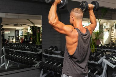 Spor salonunda aptal gibi egzersiz yapan genç ve formda bir adam. Sağlıklı bir adam aptallarla çalışıyor. Kapalı alanda çekim yapıyor..