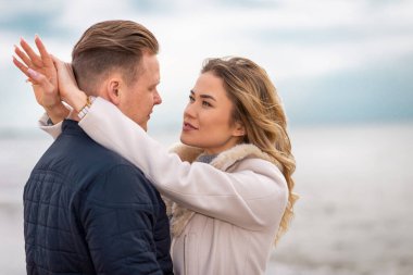 Genç çift sahilde eğleniyor ve eğleniyor. Bahar, sonbahar, sonbahar tatili..