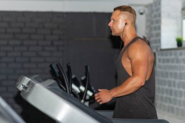 Spor giyimli genç bir adam spor salonunda koşu bandında koşuyor. Koşu bandında koşan yakışıklı bir sporcu. Kapalı alanda atış yapıyor. Koşu bandında spor salonunda koşuyor. Spor yapıyor..