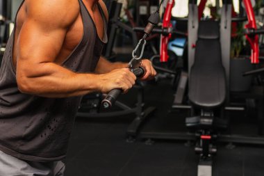 Spor salonunda egzersiz yapan kaslı bir adam, spor salonunda triseps egzersizi yapan. Güçlü çıplak erkek karın kası. Yakışıklı vücut geliştirici. Spor salonunda egzersiz yapıyor..