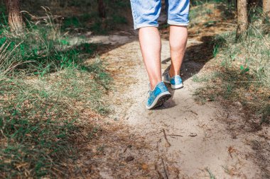 Ormanda yürüyen ya da koşan bir adam yaz doğası, spor ayakkabıları ve fotopati üzerinde egzersiz yapıyor. Yaklaş..