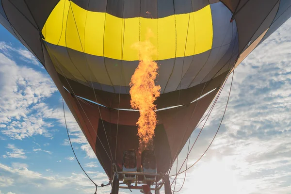 Hot flame from a gas burner light up inside of a hot air balloon at summer evening.