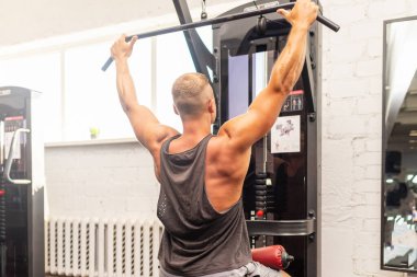 Spor salonunda egzersiz yapan kaslı bir adam, spor salonunda triseps egzersizi yapan. Güçlü çıplak erkek karın kası. Yakışıklı vücut geliştirici. Spor salonunda kapalı alanda çalışıyor..