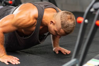 Şınav çeken genç sporcu. Spor salonunda egzersiz yapan kaslı ve güçlü bir adam. Güç ve motivasyon kavramı. Kesildi..