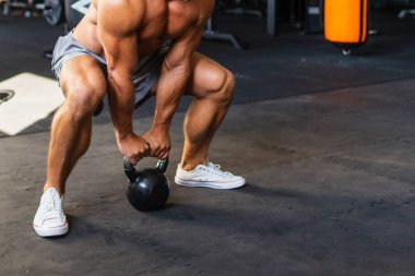 Muscular shirtless man workout with kettle bell.man focused on lifting a dumbbell exercise in a gym.Copy space.Cropped image.