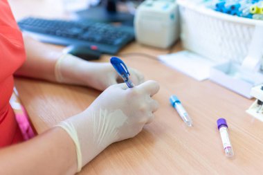 Bulanık bir arka planda laboratuvar kliniğinde test tüplerine yazı yazan bilim adamı..