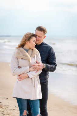 Genç çift sahilde eğleniyor ve eğleniyor. Bahar, sonbahar, sonbahar tatili..