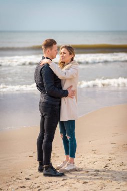 Genç çift sahilde eğleniyor ve eğleniyor. Bahar, sonbahar, sonbahar tatili..