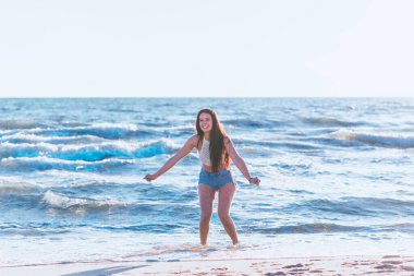 Yazın denizde oynayan genç bir kadın. Deniz suyunda eğlenen bir kadın. Sahilde eğlenen neşeli genç bir kadın. Deniz suyunda dinleniyor ve tatilin tadını çıkarıyor..