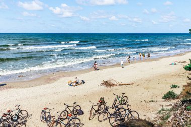Birkaç turistli güzel kumlu plaj. Kumda bisiklet. Klaipeda, Litvanya. 12-08-2021.