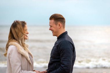 Genç çift kumların üzerinde eğleniyor ve eğleniyorlar. Yaz, bahar, sonbahar tatili..