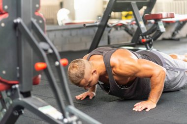 Şınav çeken genç sporcu. Spor salonunda egzersiz yapan kaslı ve güçlü bir adam. Spor kıyafetli genç yakışıklı bir adamın spor salonunda şınav çekmesi..