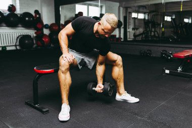 Genç sporcu spor salonunda biceps çalışıyor. Spor salonunda ağırlık kaldıran kaslı bir gencin yakın çekimi. Yakın plan..