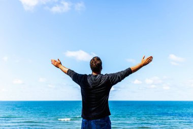 Kafkasyalı adam kollarını açıp okyanusu izliyor. Kollarını uzatmış mutlu bir adam. Yaz günü kollarını dikiz aynasından kaldırmış bir adam..