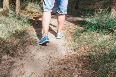 Ormanda yürüyen ya da koşan bir adam yaz doğası, spor ayakkabıları ve fotopati üzerinde egzersiz yapıyor. Yaklaş..