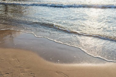 Kumlu akşam kumsalında denizin yumuşak dalgası. Odaklanma, bulanık görüntü. Boşluğu kopyala.
