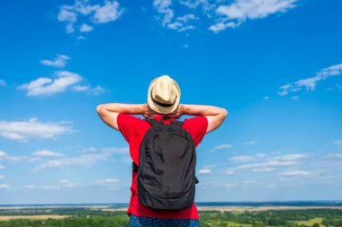 Orman manzarasına hayran olan genç bir adam. Arka planda vahşi ormanla birlikte yaz günü tek başına ayakta duran genç bir adam. Seyahat yaşam tarzı kavramı arka görünümü