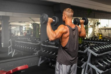 Spor salonunda aptal gibi egzersiz yapan genç ve formda bir adam. Sağlıklı bir adam aptallarla çalışıyor. Kapalı alanda çekim yapıyor..