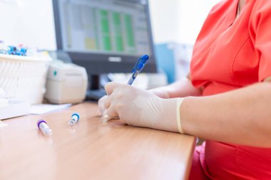 Bulanık bir arka planda laboratuvar kliniğinde test tüplerine yazı yazan bilim adamı..
