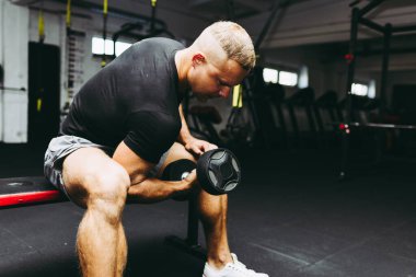 Genç sporcu spor salonunda biceps çalışıyor. Spor salonunda ağırlık kaldıran kaslı bir gencin yakın çekimi. Yakın plan..