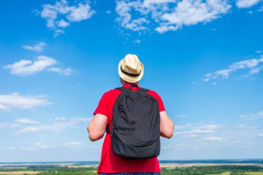 Orman manzarasına hayran olan genç bir adam. Arka planda vahşi ormanla birlikte yaz günü tek başına ayakta duran genç bir adam. Seyahat yaşam tarzı kavramı arka görünümü