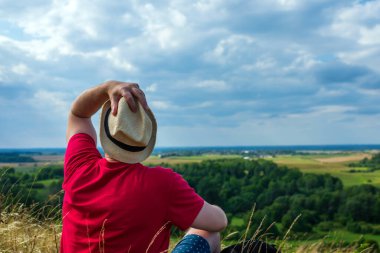 Orman manzarasına hayran olan genç bir adam. Arka planda vahşi ormanla birlikte yaz günü tek başına ayakta duran genç bir adam. Seyahat yaşam tarzı kavramı arka görünümü