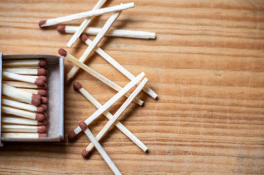 Eski ahşap arka planda kutuda kibrit var. Yakın plan çekim. Açık kibrit kutusundaki kibrit çöpleri düz yerde yatar, boşluğu kopyalar. Açık kibrit kutusundaki kibrit kutusuyla bir karton altında eşleşir. Seçili odak noktası.