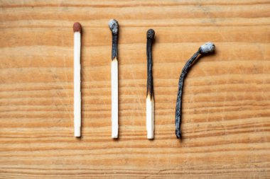 Bir sıra yanmış kibrit ve ahşap arka plan, üst manzara, yakın çekim. İnsan yaşamının aşamaları kavramları veya insan yaşamının farklı aşamaları kavramları. Seçmeli odaklanma.