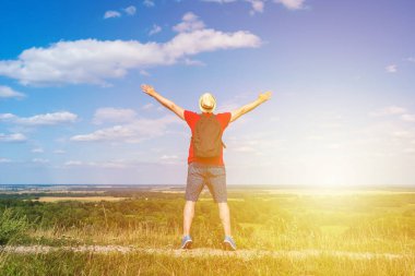 Orman manzarasına hayran olan genç bir adam. Arka planda vahşi ormanla birlikte yaz günü tek başına ayakta duran genç bir adam. Seyahat yaşam tarzı kavramı arka görünümü